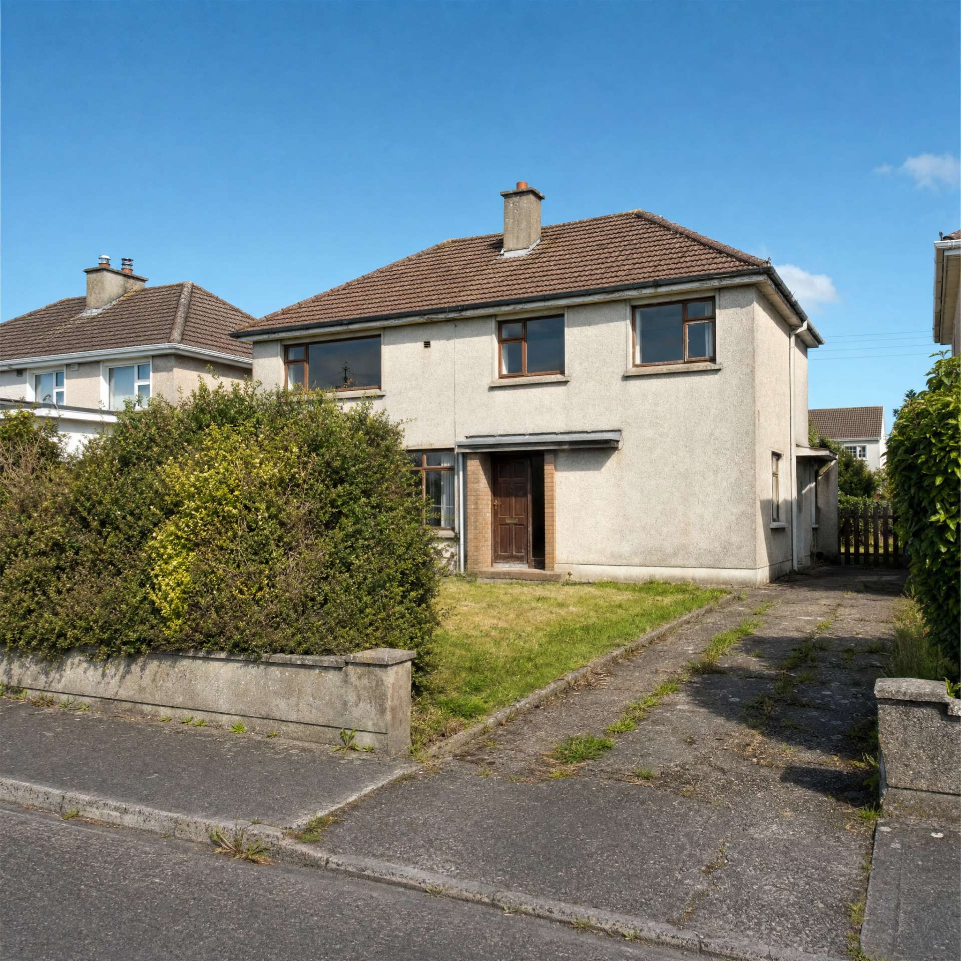 A dated pebble-dash Cork house before renovation — old timber windows, an overgrown hedge and a weedy drive.