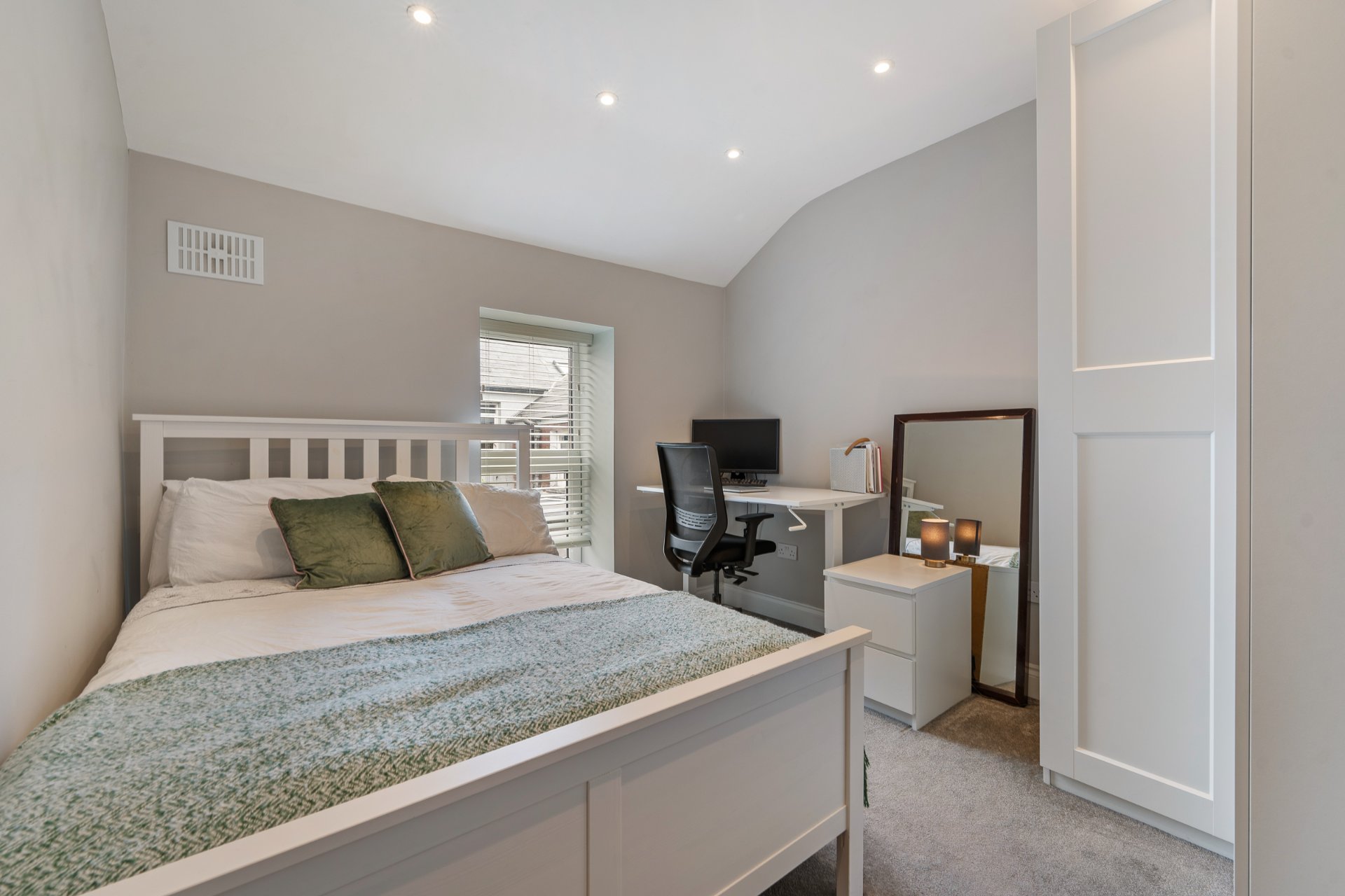 A second bedroom set up as a bedroom and home office, with a built-in desk.