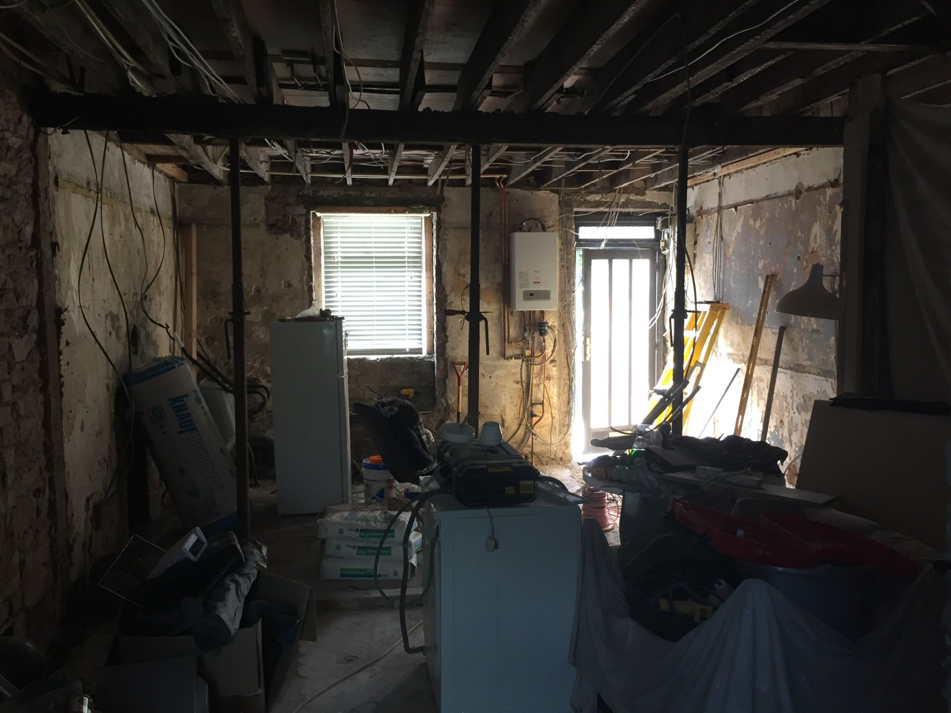 The house mid-renovation — stripped back to bare stone walls and joists, with steel props holding the structure during the works.