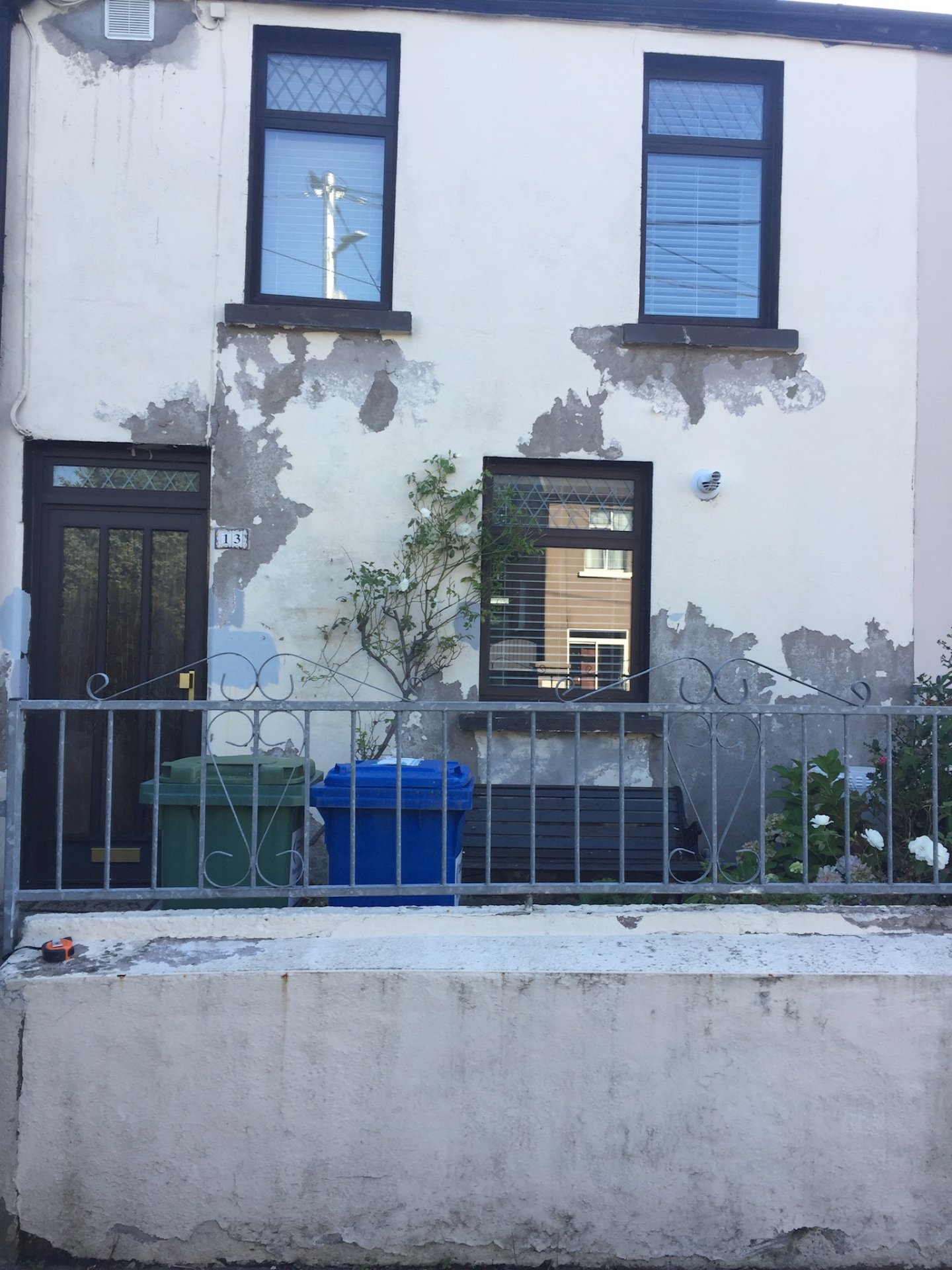 The same house before renovation — cracked, peeling render and dated timber windows.
